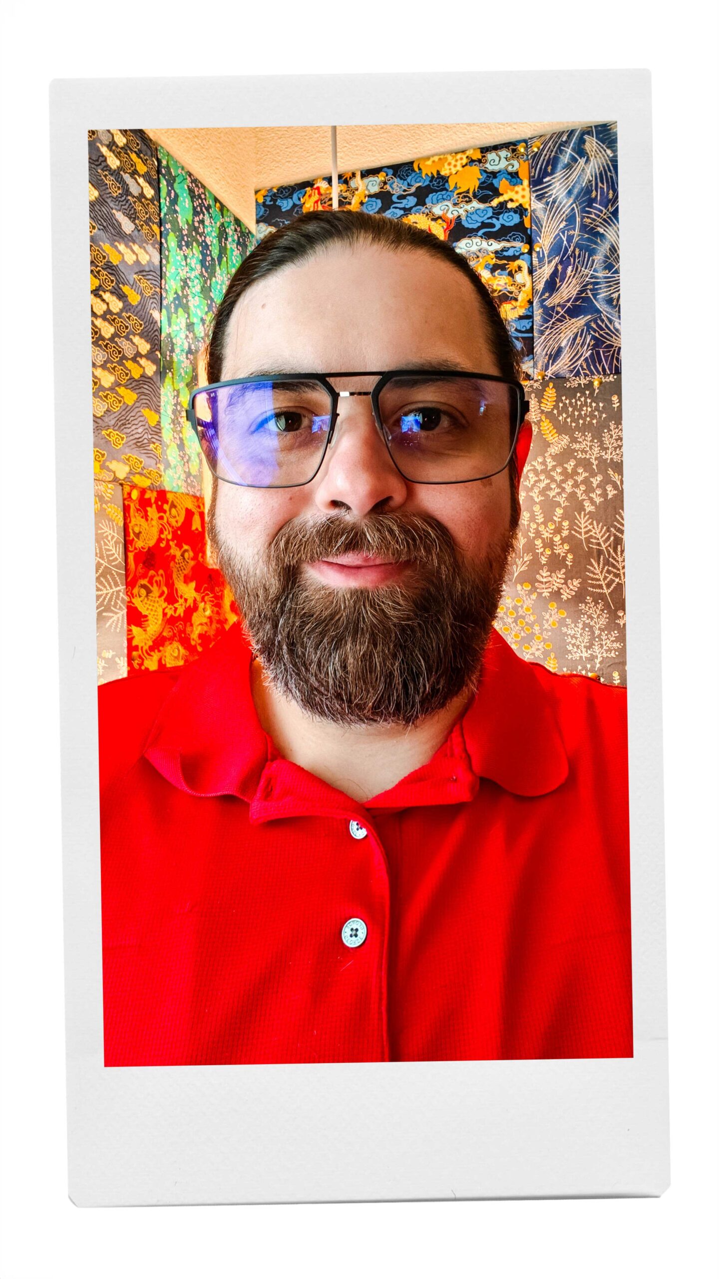 A photo of Andy Melton wearing a red polo and large frame blue light blocking computer glasses.